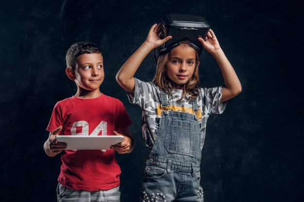 Glücklicher lächelnder Junge hält Tablet, während Mädchen vr-Brille trägt.