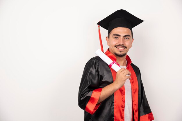 Glücklicher männlicher Student mit Diplom, das auf Weiß steht.