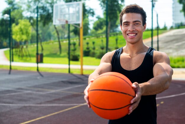 Glücklicher Mann, der einen Ball zur Kamera zeigt