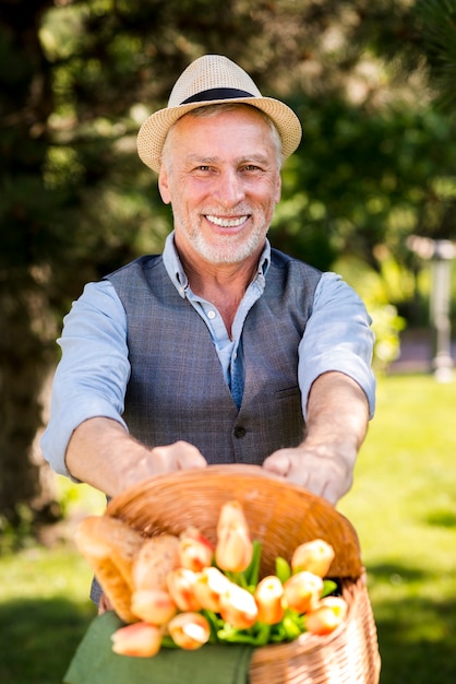 Glücklicher Mann, der einen Korb mit Blumen hält