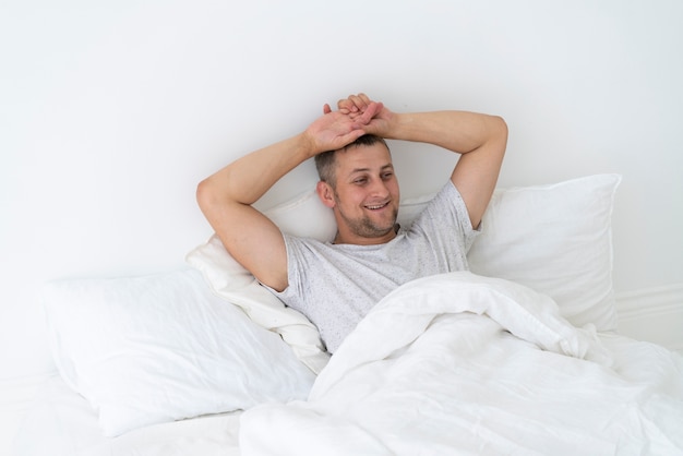 Glücklicher Mann, der in das Schlafzimmer legt