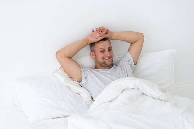 Glücklicher Mann, der in das Schlafzimmer legt