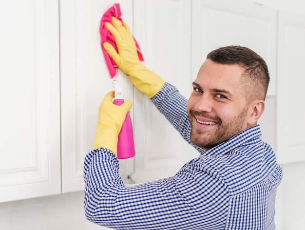 Glücklicher Mann, der Küchenschränke reinigt