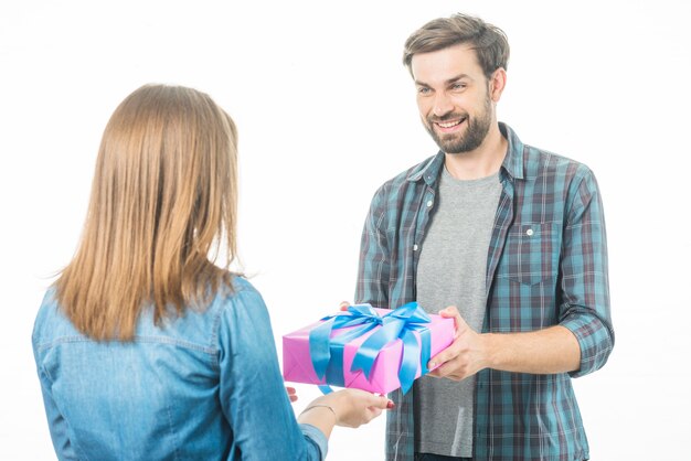 Glücklicher Mann, der seiner Freundin Geschenkbox auf weißem Hintergrund gibt