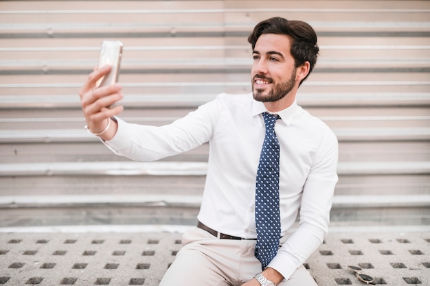 Kostenloses Foto glücklicher mann, der selfie mit smartphone nimmt