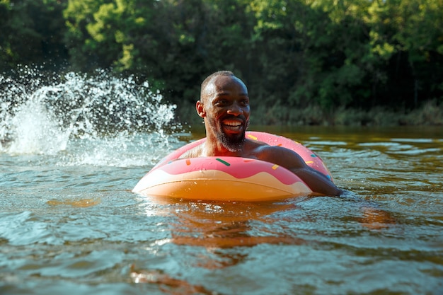 Glücklicher Mann, der Spaß hat, lacht und im Fluss schwimmt