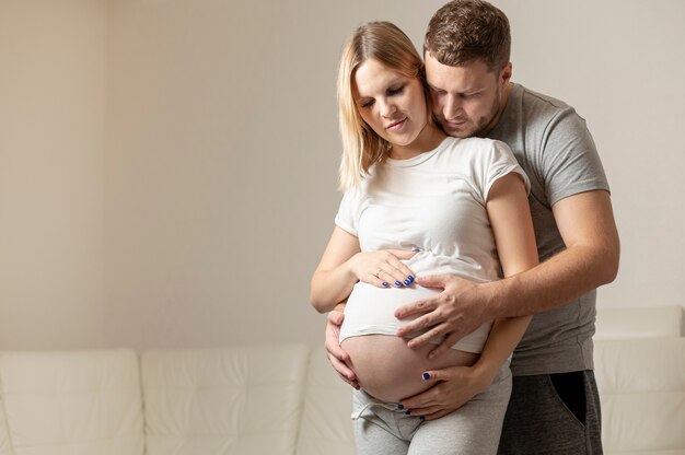 Glücklicher Mann, der zu Hause schwangere Frau umarmt