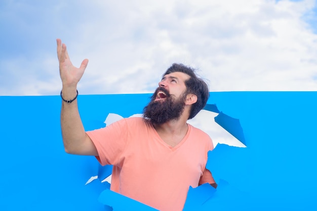 Glücklicher mann durch loch in blauem papier durch papierwerbung glückliche emotionen lächelnd rabattverkauf