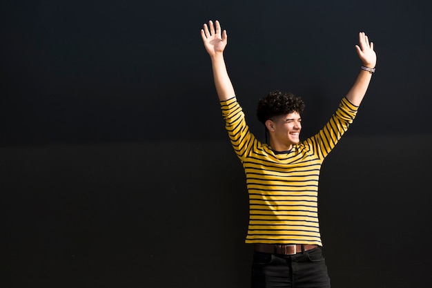 Kostenloses Foto glücklicher mann in gestreiftem hemd mit den händen oben im studio