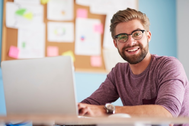 Kostenloses Foto glücklicher mann mit laptop-computer im büro