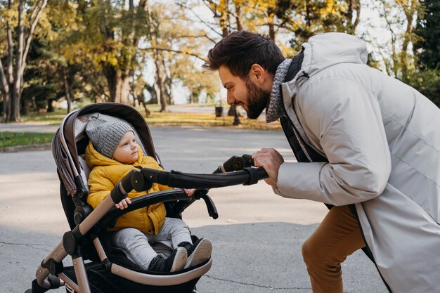 Glücklicher Mann mit seinem Kind draußen im Kinderwagen