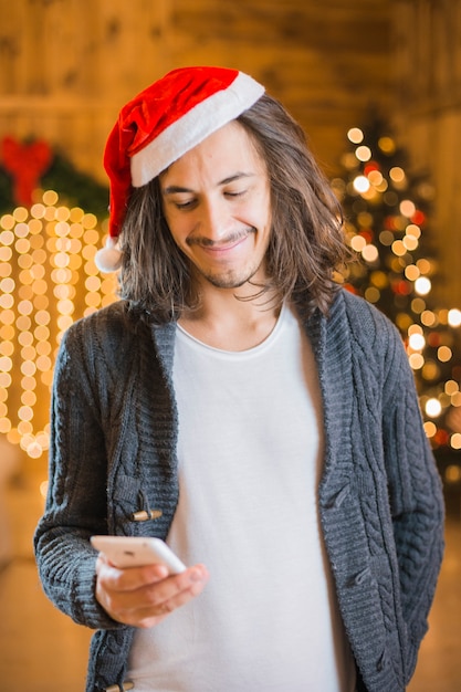 Glücklicher Mann mit Smartphone am Weihnachten