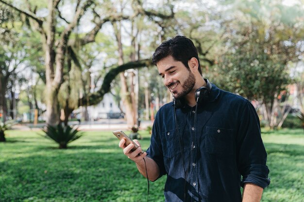 Glücklicher Mann mit Telefon im grünen Park