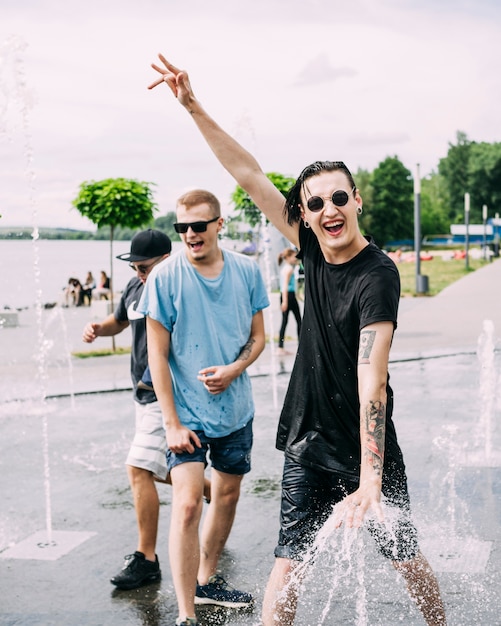 Glücklicher Mann nahe dem Brunnen, der Spaß mit Freunden macht