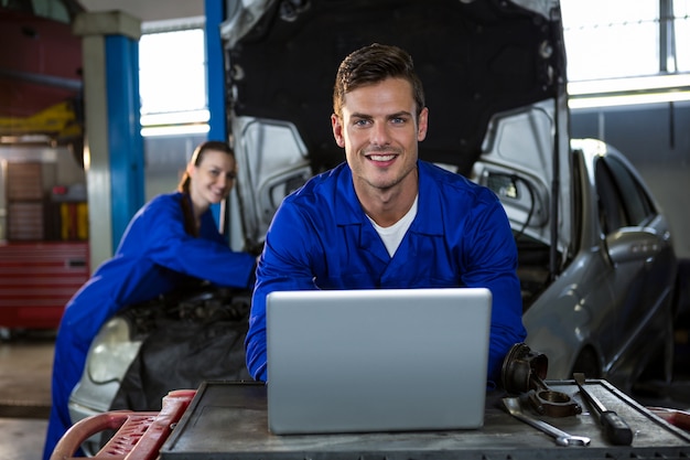 Kostenloses Foto glücklicher mechaniker arbeiten auf laptop