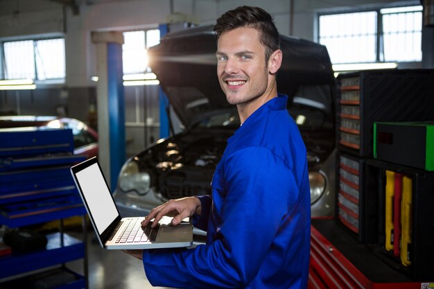 Glücklicher Mechaniker arbeiten auf Laptop