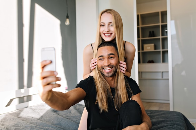 Glücklicher Morgen in der modernen Wohnung des freudigen Paares, das Spaß zusammen hat. Selfie machen, wahre positive Emotionen, Liebe, Freizeit, fröhliche Stimmung, Lächeln, Freude, Zusammengehörigkeit ausdrücken