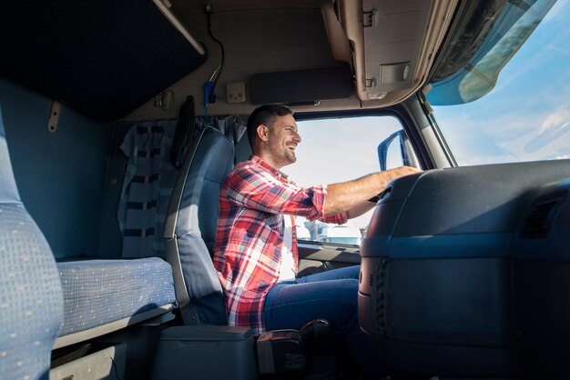 Glücklicher professioneller LKW-Fahrer mittleren Alters in Freizeitkleidung, die LKW auf Autobahn fährt
