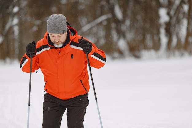 Glücklicher reifer Mann im Winterpark. Senior Activewear Trekking im Wald zur freien Verfügung