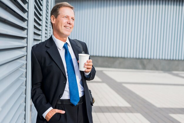 Glücklicher reifer Mann mit Tasse Kaffee an draußen