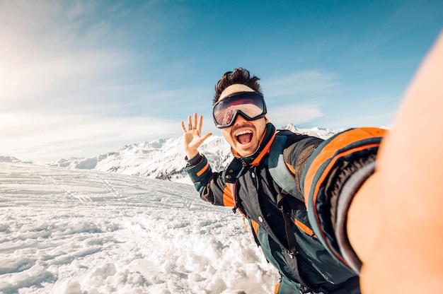 Glücklicher skifahrer, der ein selfie in den bergen macht junger mann, der spaß beim skifahren im winterwald hat Premium Fotos