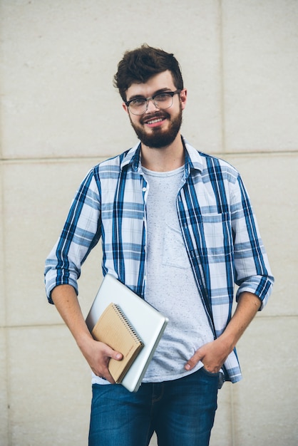 Kostenloses Foto glücklicher student, der auf der kamera draußen hält texrbooks aufwirft