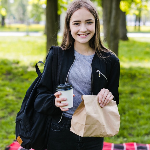 Glücklicher Student mit Kaffee und Papiertüte