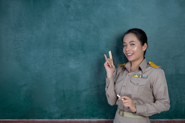 glücklicher thailändischer Lehrer im offiziellen Outfit, der vor Tafel posiert