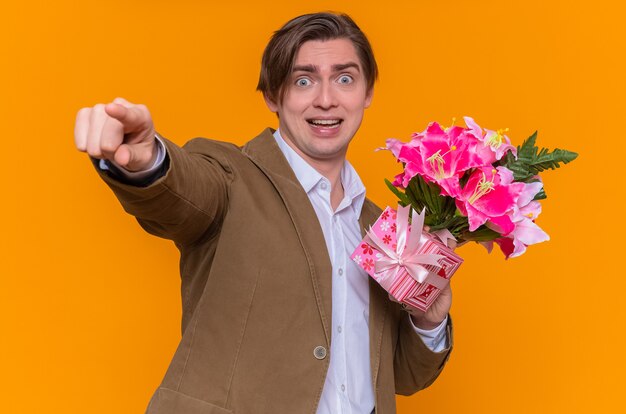Glücklicher und aufgeregter junger Mann, der Blumenstrauß zeigt