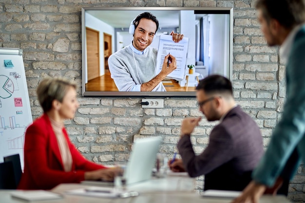 Glücklicher Unternehmer, der per Videokonferenz an einem Geschäftstreffen teilnimmt und mit seinen Kollegen über Papierkram spricht