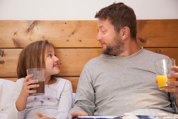 Glücklicher Vater beim Frühstück im Bett mit seiner Tochter