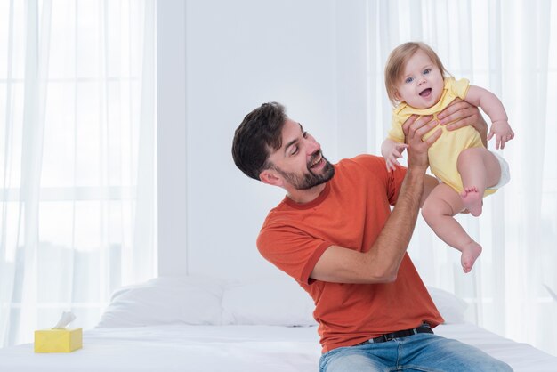 Glücklicher Vater, der Baby im Bett hält