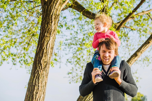 Glücklicher Vater mit seinem Sohn auf den Schultern im Freien