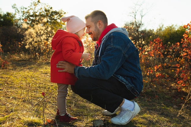 Glücklicher Vater und kleine süße Tochter, die im sonnigen Herbsttag den Waldweg hinuntergehen