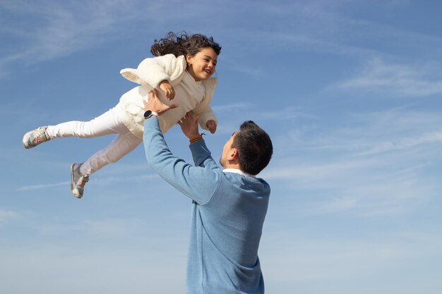 Glücklicher Vater und Tochter reisen zusammen. Japanische Familie geht spazieren, lacht, albert herum, hebt Kind hoch. Papa Freizeit, Familienzeit, Elternschaft hell