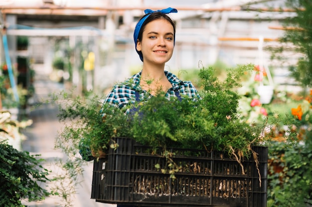 Kostenloses Foto glücklicher weiblicher gärtner, der kiste mit frischen anlagen hält
