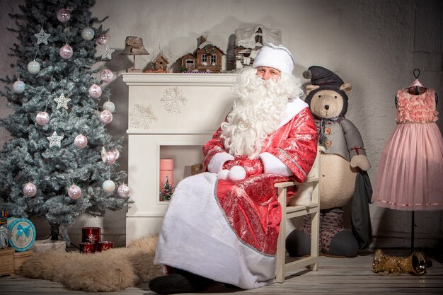 Glücklicher Weihnachtsmann, der auf der Weihnachtsdekoration sitzt