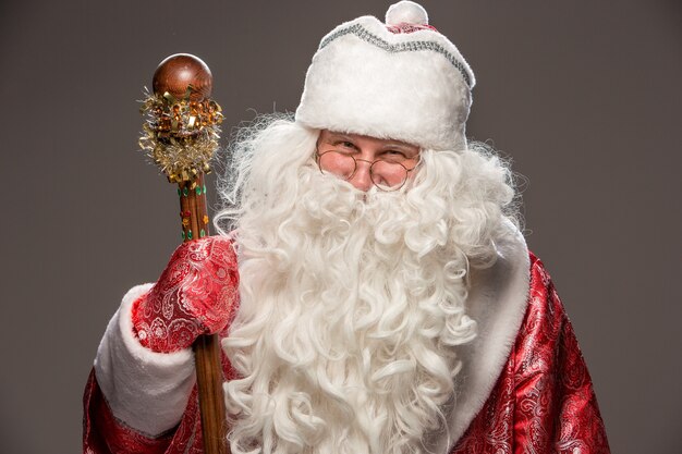 Kostenloses Foto glücklicher weihnachtsmann in brille mit personal, das kamera auf schwarz betrachtet