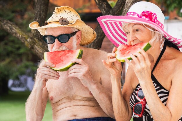 Glückliches älteres paar, das party im swimmingpool hat