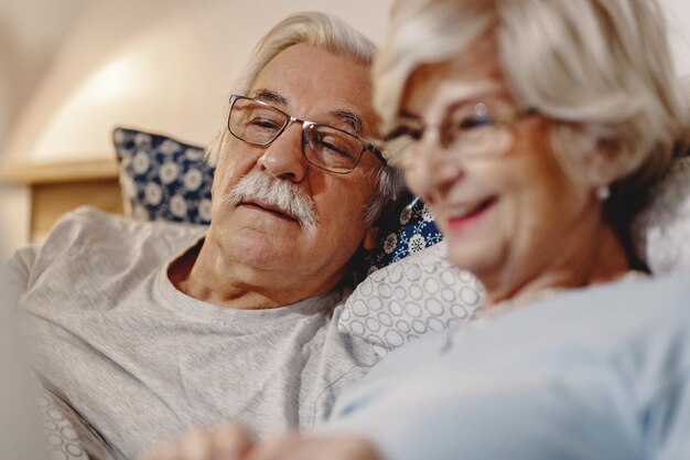 Glückliches älteres Paar, das sich im Schlafzimmer entspannt Der Fokus liegt auf dem Menschen
