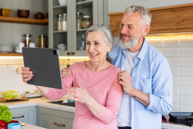 Glückliches älteres Paar mit Tablette mittlerer Schuss