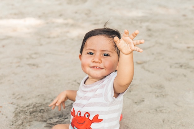 Kostenloses Foto glückliches baby, das auf sand sitzt