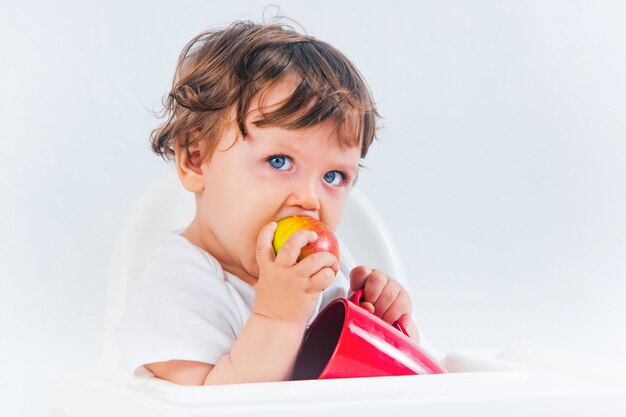 Glückliches Baby, das sitzt und isst