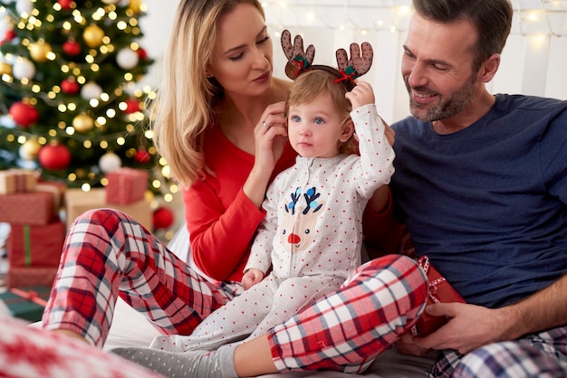 Glückliches baby mit familie am weihnachtsmorgen