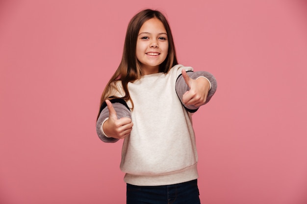 Glückliches Brunettemädchen, das sich Daumen und das Lächeln zeigt