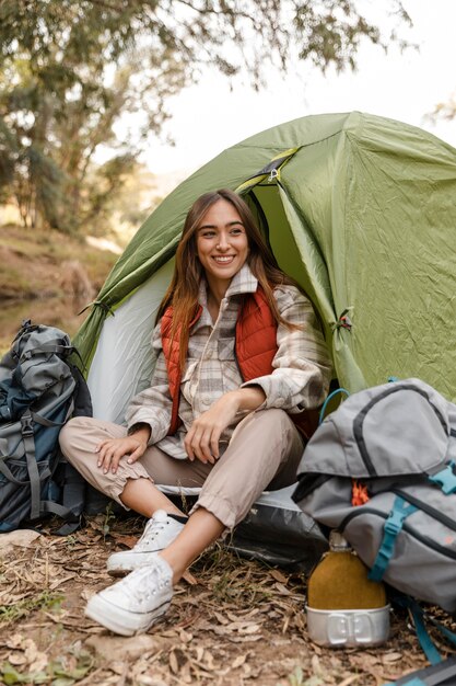 Glückliches Campingmädchen im Wald, der im Zelt sitzt