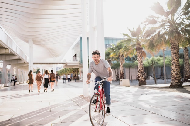 Kostenloses Foto glückliches fahrrad des jungen mannes reitauf pflasterung