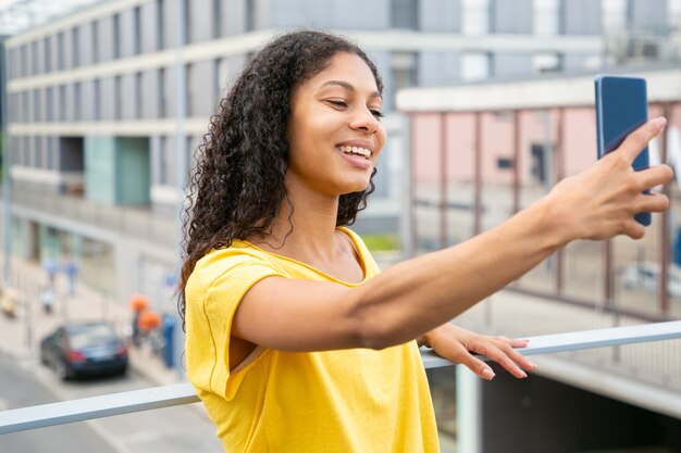 Glückliches frohes lateinisches Mädchen, das draußen selfie nimmt