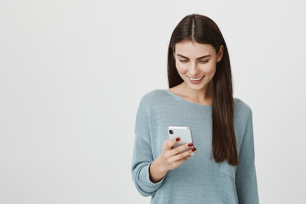 Glückliches gut aussehendes Frauennachrichten, das Handy benutzt