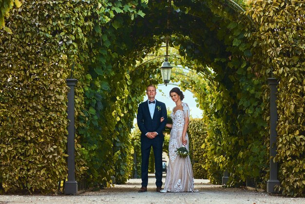 Glückliches Hochzeitspaar geht durch den schönen Garten.